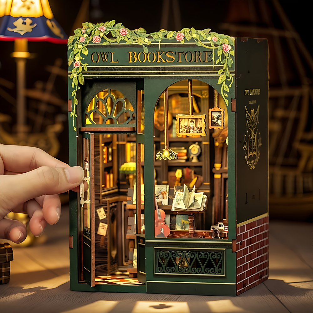 Un coin livre miniature en bois vert de style maison de poupée, avec des détails complexes et un éclairage intérieur.
