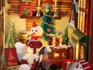 Un village de Noël miniature avec un bonhomme de neige, un arbre décoré et de petits cadeaux.