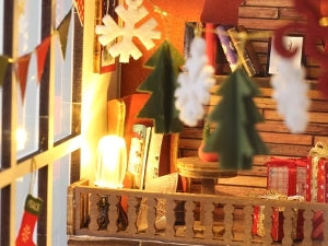 Maison de poupée miniature sur le thème de Noël avec des décorations et des éclairages festifs.