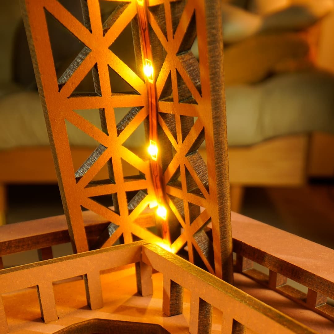Une maquette de Tour Eiffel en bois éclairée par une guirlande de petites lumières chaudes.