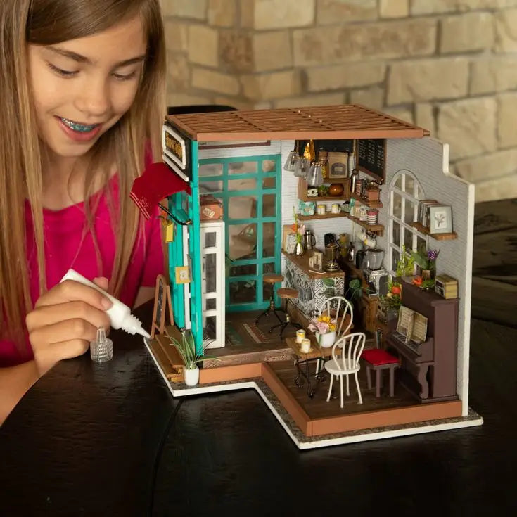Un kit de maison de poupée miniature et détaillée ressemblant à un café confortable avec des meubles et des accessoires.