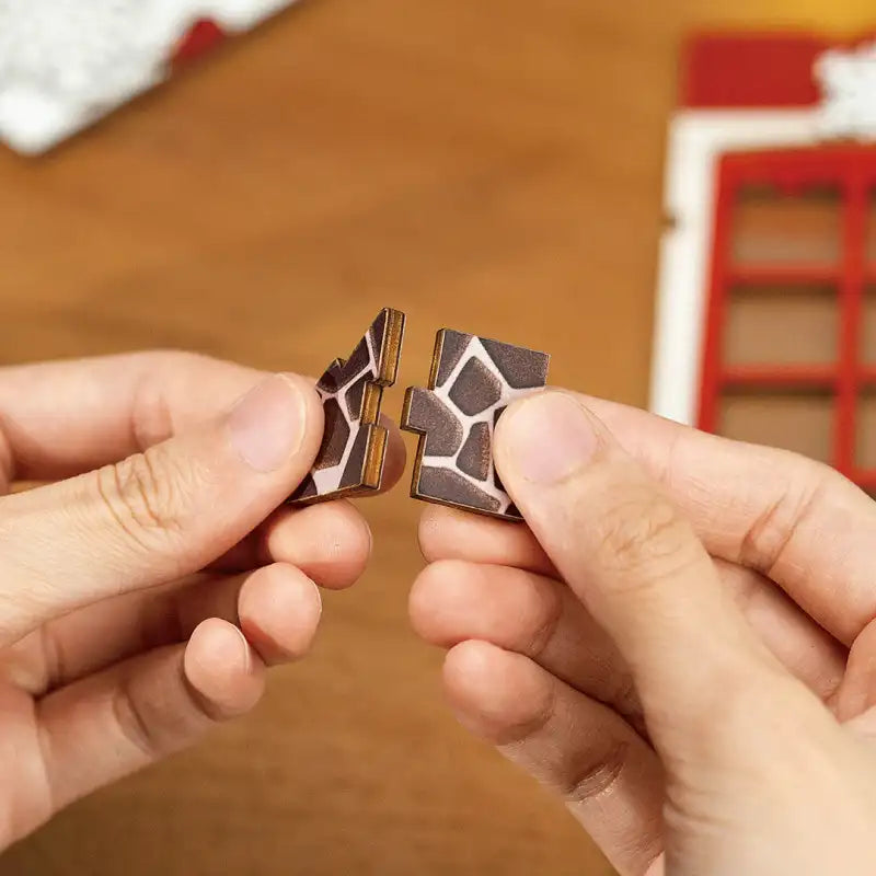Deux pièces de puzzle en bois qui s’emboîtent les unes dans les autres, avec un motif de girafe marron et blanc.