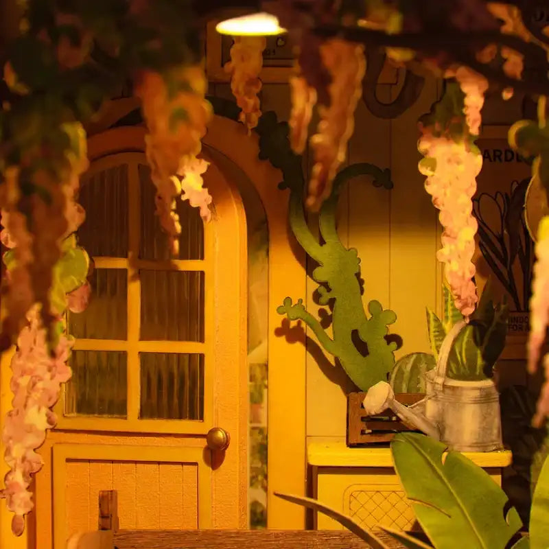 Une maison de poupée miniature jaune avec une façade détaillée et des glycines en fleurs.