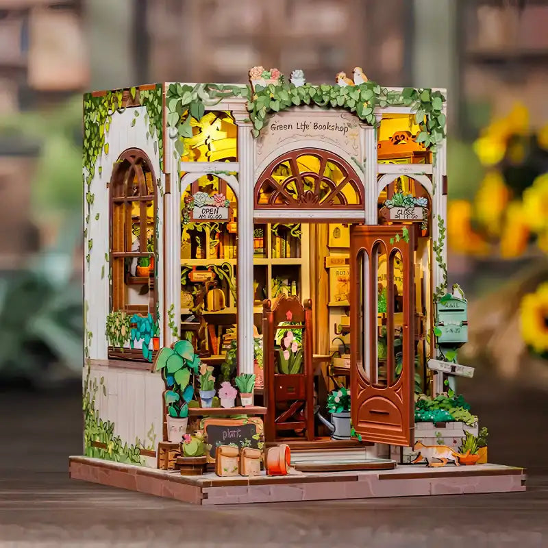 Kit d’artisanat miniature illuminé ’Green Life Bookshop’, comprenant des détails complexes d’une façade de librairie avec des plantes en pot et une porte ouverte.