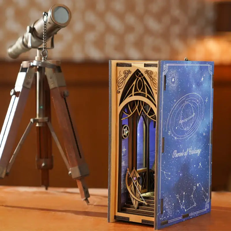 Un diorama en bois en forme de livre ouvert avec une couverture à thème céleste.