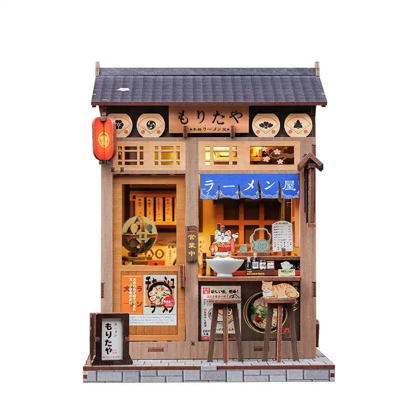 Maquette miniature en bois d’un magasin de ramen japonais, avec des détails complexes et des lumières fonctionnelles.