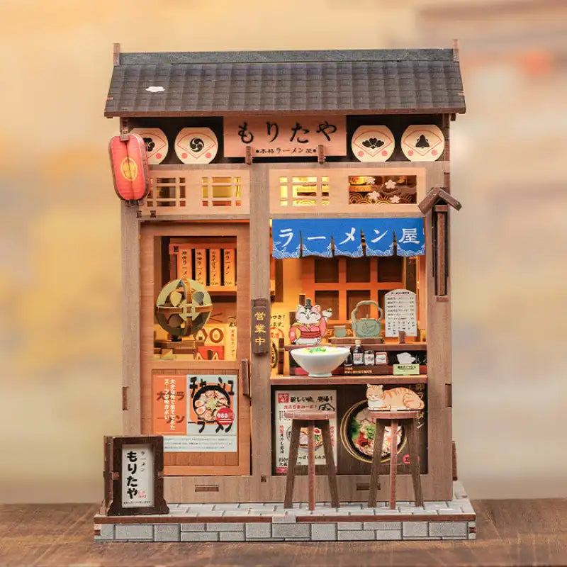 Modèle miniature en bois d’un magasin de ramen japonais, avec des détails et des éclairages complexes.