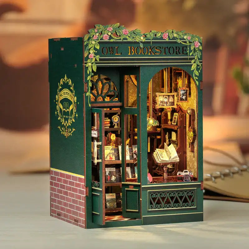 Un modèle miniature de librairie hibou en bois vert avec des détails complexes et un éclairage intérieur.