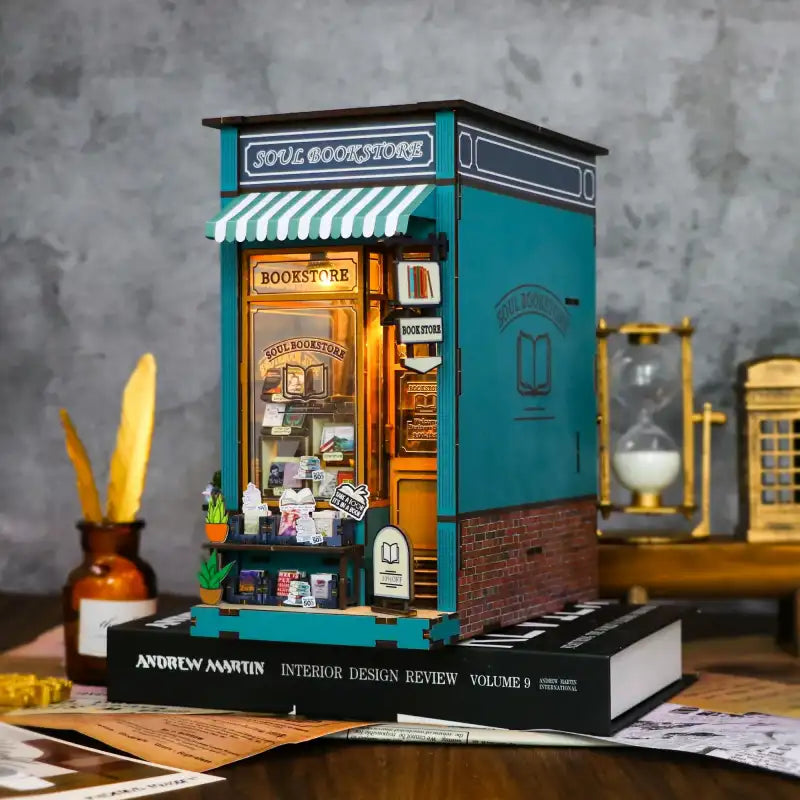 Un modèle de librairie miniature de couleur sarcelle avec un intérieur éclairé et un auvent rayé.