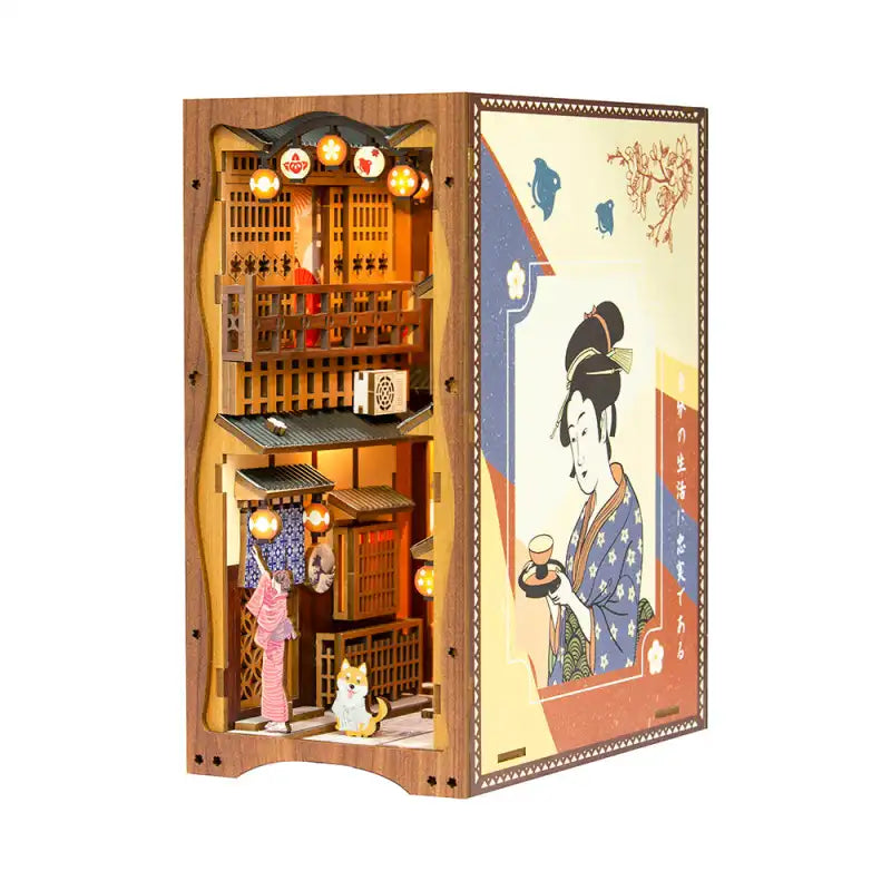 Un coin livre représentant une scène de rue japonaise miniature avec des lanternes illuminées et une illustration traditionnelle de style ukiyo-e sur le côté.