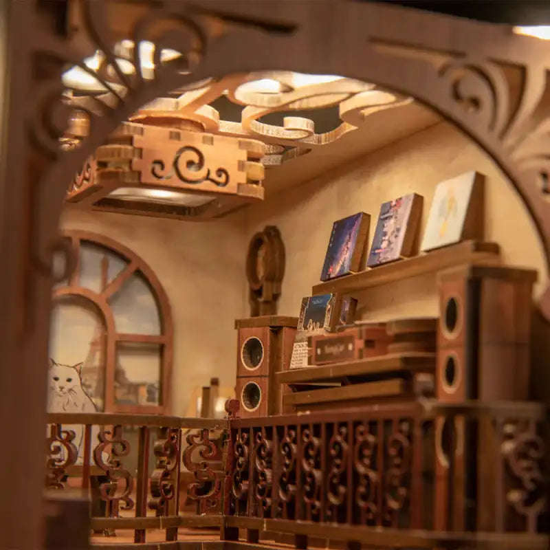 Une pièce miniature en bois, de fabrication artisanale, avec des balustrades décoratives, une fenêtre et des étagères de livres.