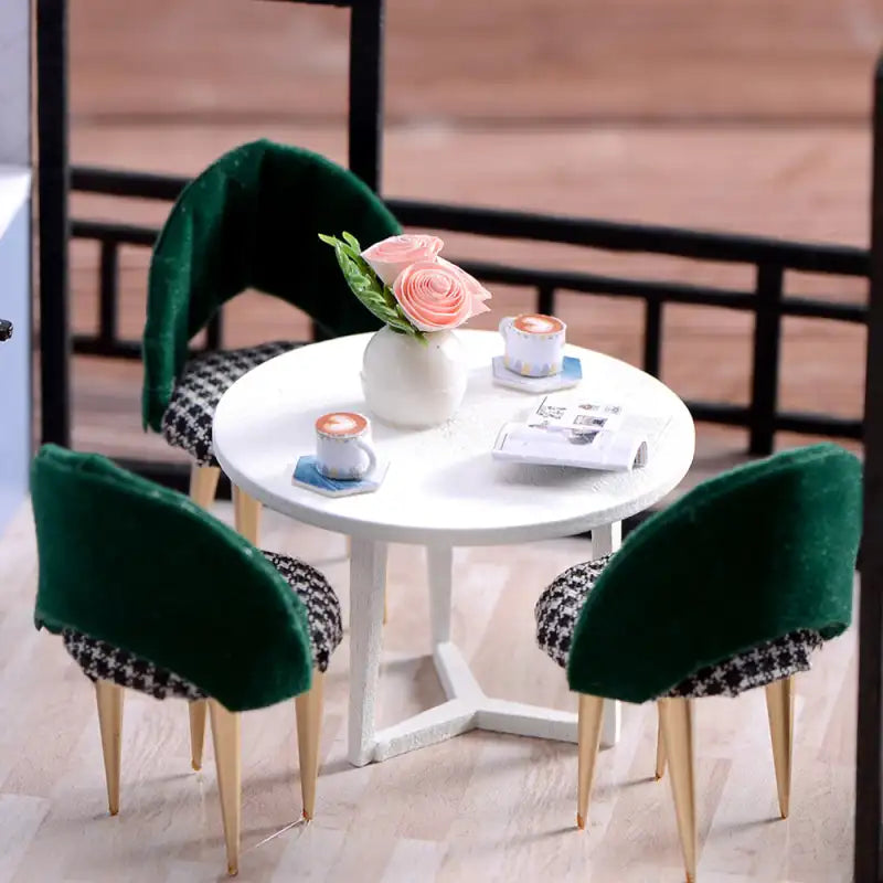 Une table ronde blanche avec trois chaises vertes et noires en pied de poule.