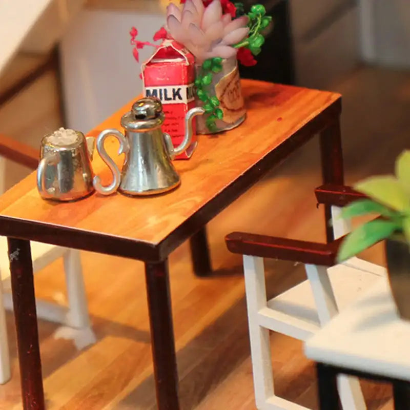 Table miniature en bois avec service à thé métallique et plantes décoratives.