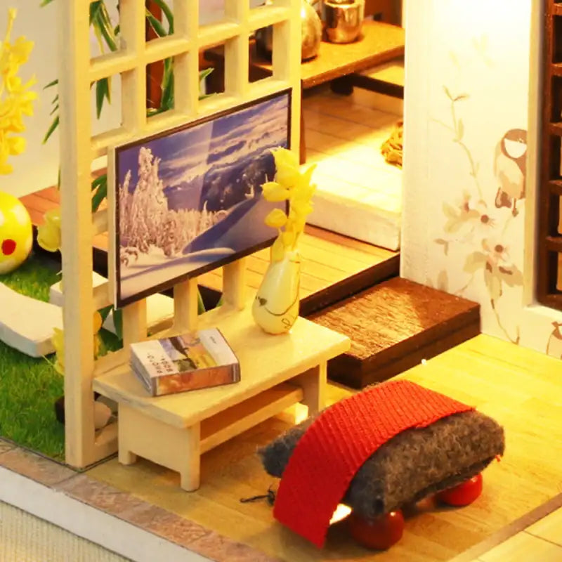 Salle de séjour d’une maison de poupée miniature avec une scène d’hiver à la télévision.