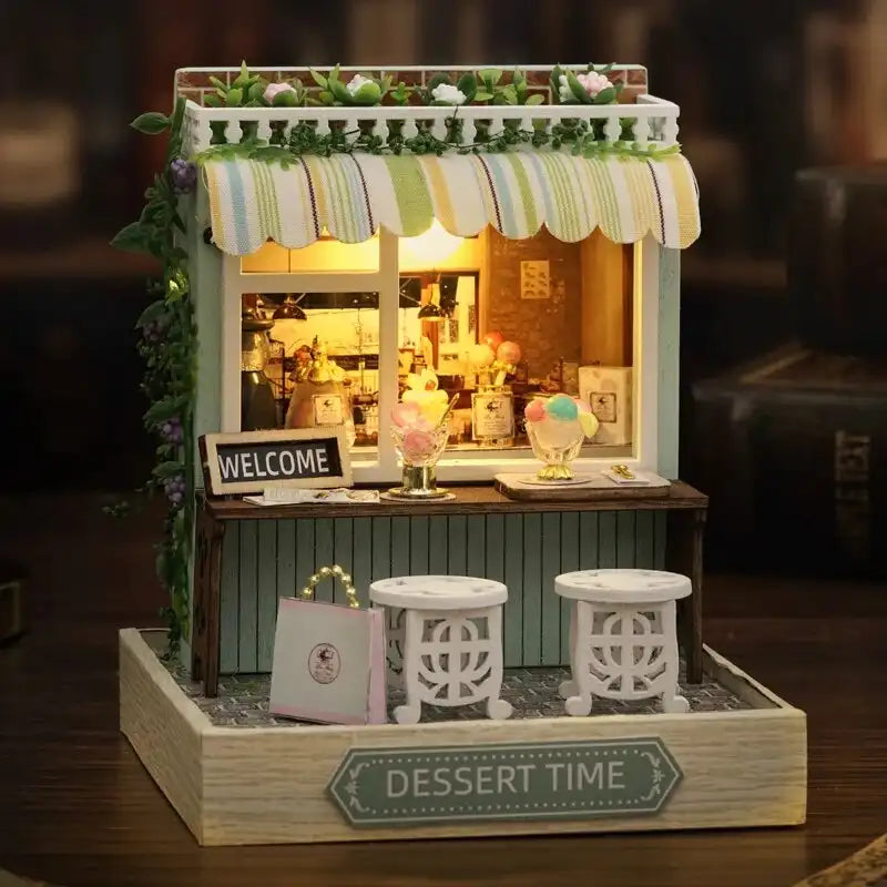 Une boutique de desserts miniature avec un auvent rayé et deux tabourets.