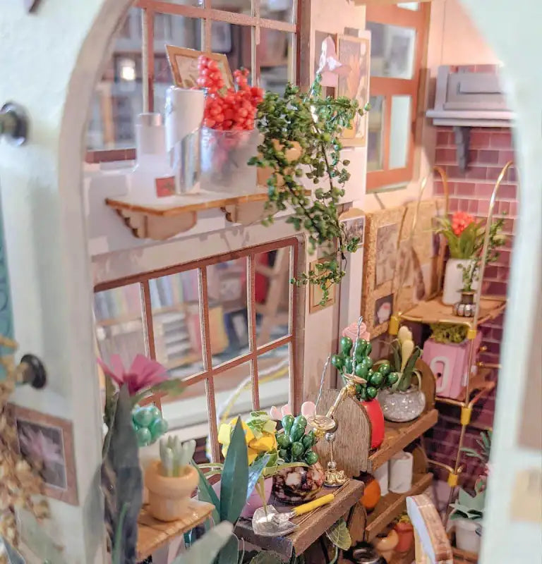 Pièce miniature pour maison de poupée, très détaillée, avec de nombreuses plantes et décorations.