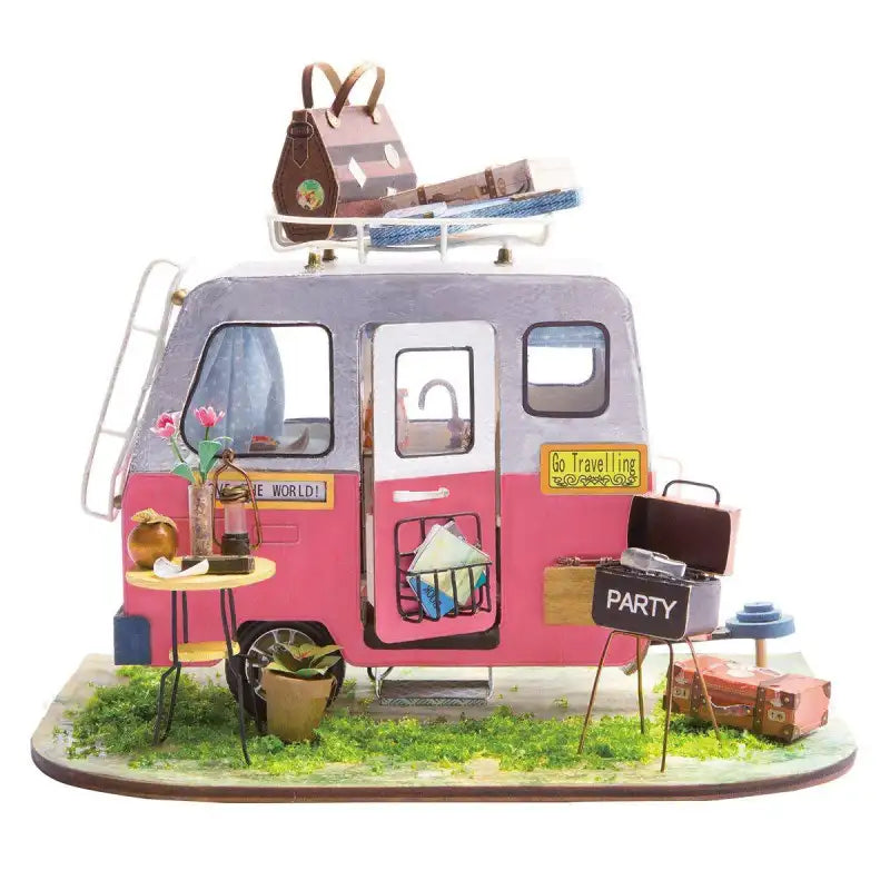 Modèle de camping-car miniature rose et gris avec galerie de toit, meubles d’extérieur et accessoires.