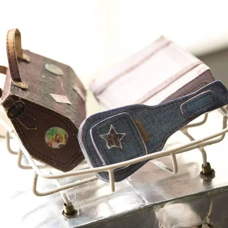 Valise marron miniature et accessoire en forme de guitare en denim.