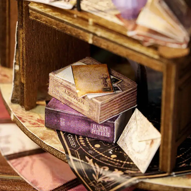 Livres miniatures et petite enveloppe sur un tapis décoratif.