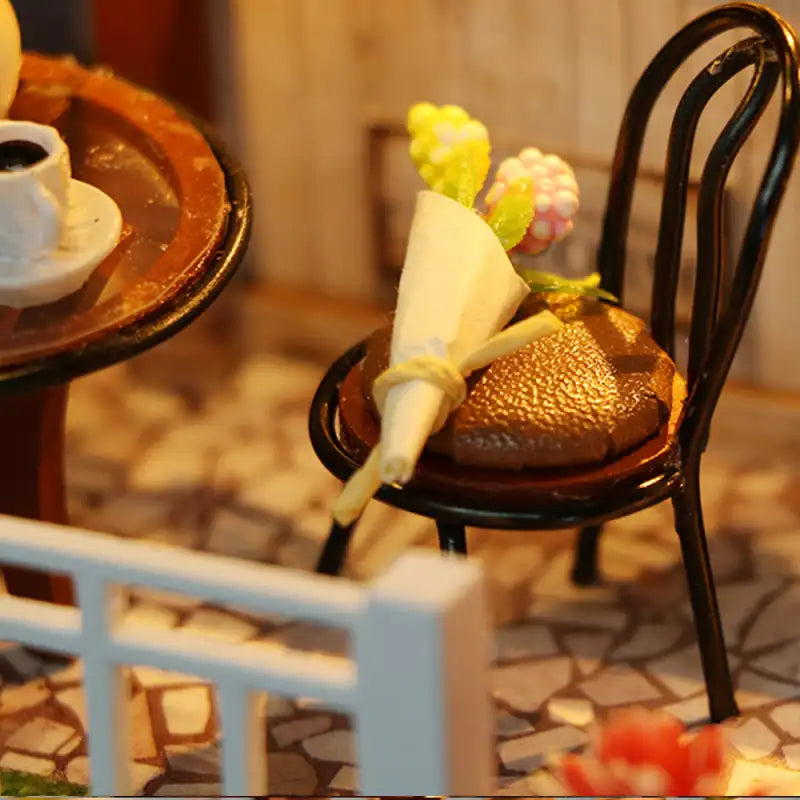 Chaise noire miniature avec un dessert au chocolat et un petit bouquet.