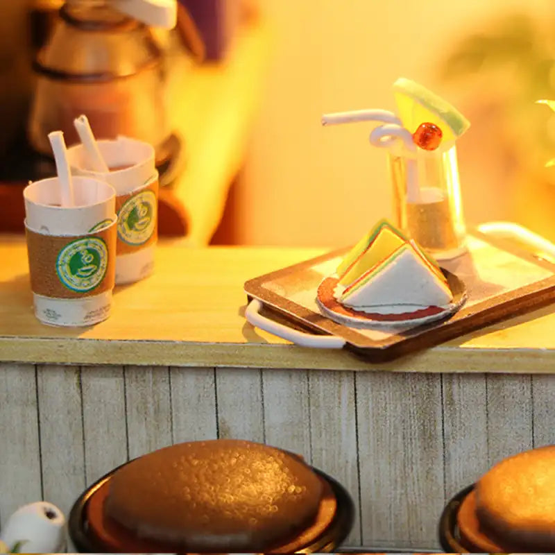 Scène de café miniature avec boissons et desserts.