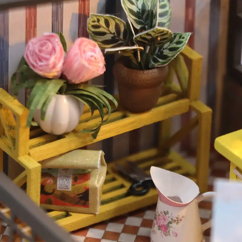 Jardinière jaune miniature avec fleurs en pot et matériel de jardinage.