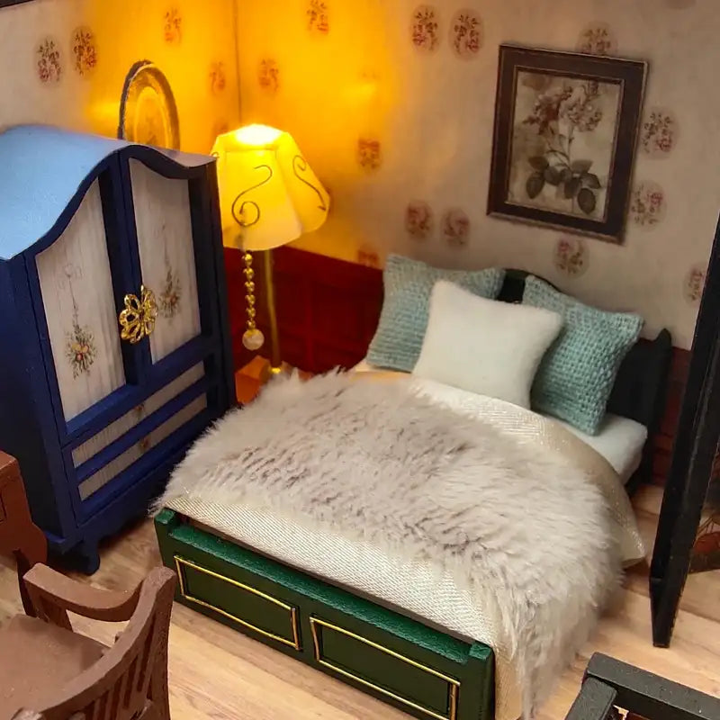Un ensemble de chambre à coucher miniature pour maison de poupée comprenant une armoire bleu foncé, un lit avec un cadre vert et une couverture grise duveteuse, et un lampadaire décoratif.