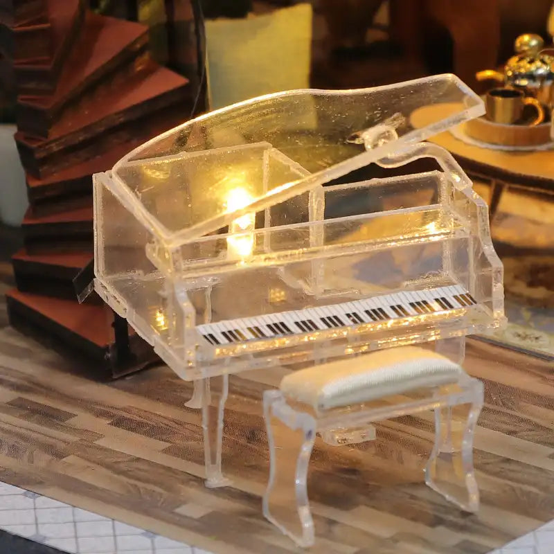 Un piano à queue miniature transparent avec un banc assorti, éclairé par des lumières internes.