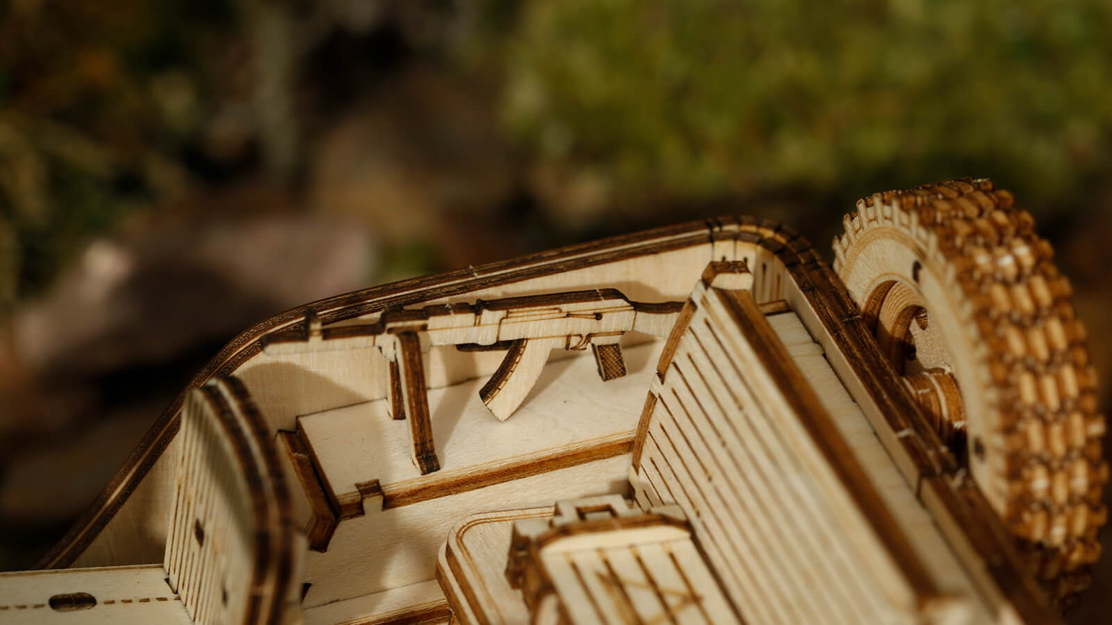 Modèle en bois d’un véhicule de style militaire à toit ouvert avec un fusil miniature à l’intérieur.