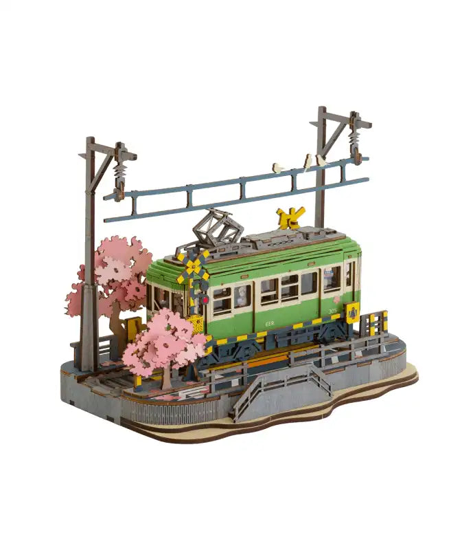 Maquette en bois d’un tramway vert avec des cerisiers en fleurs.