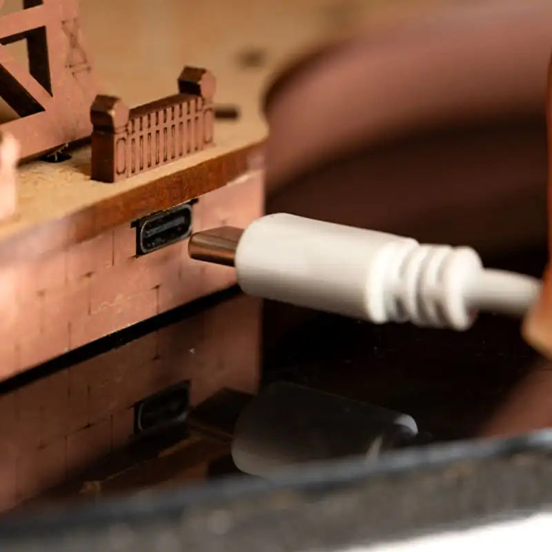 Un câble USB-C blanc en train d’être branché sur un appareil électronique en bois.