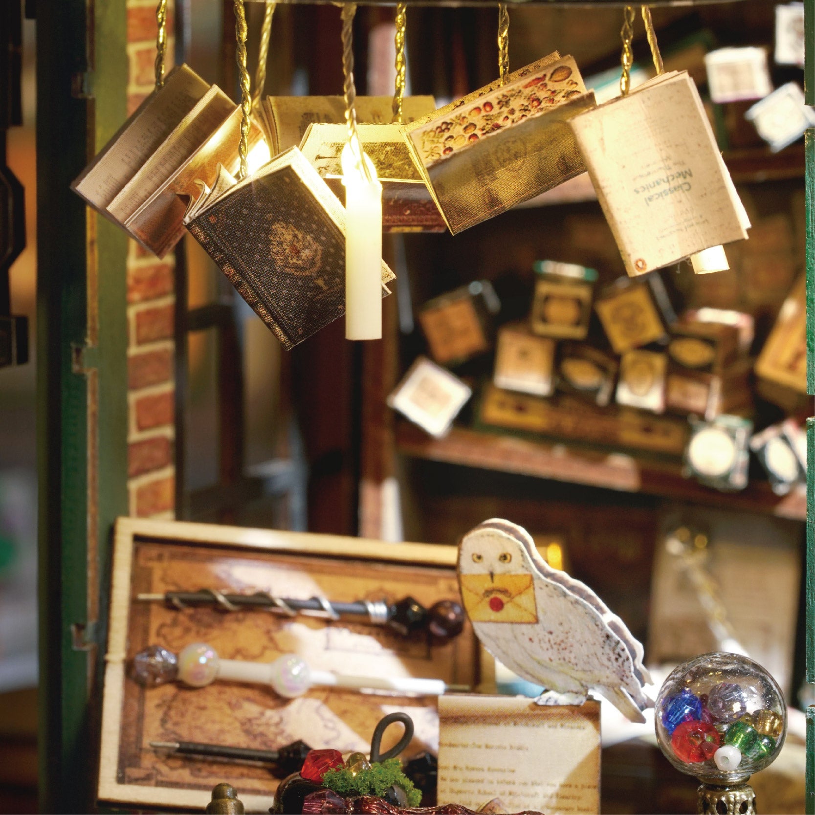 Une présentation décorative de livres de sorciers miniatures, de baguettes et d’une figurine de hibou.