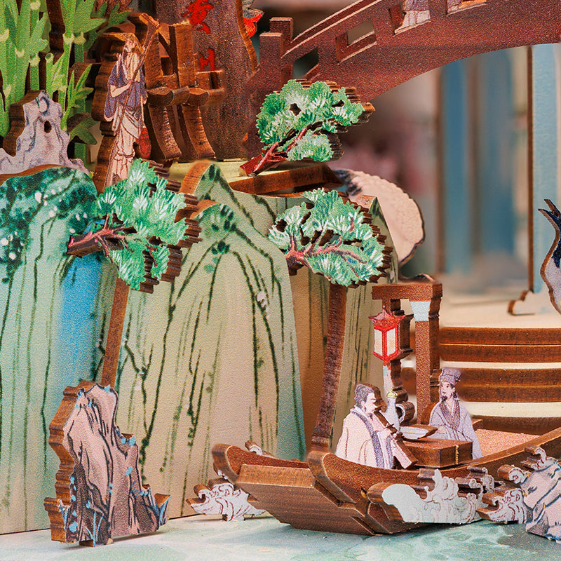 Diorama en bois complexe représentant un paysage traditionnel de l’Asie de l’Est avec des personnages dans un bateau et sur un pont.