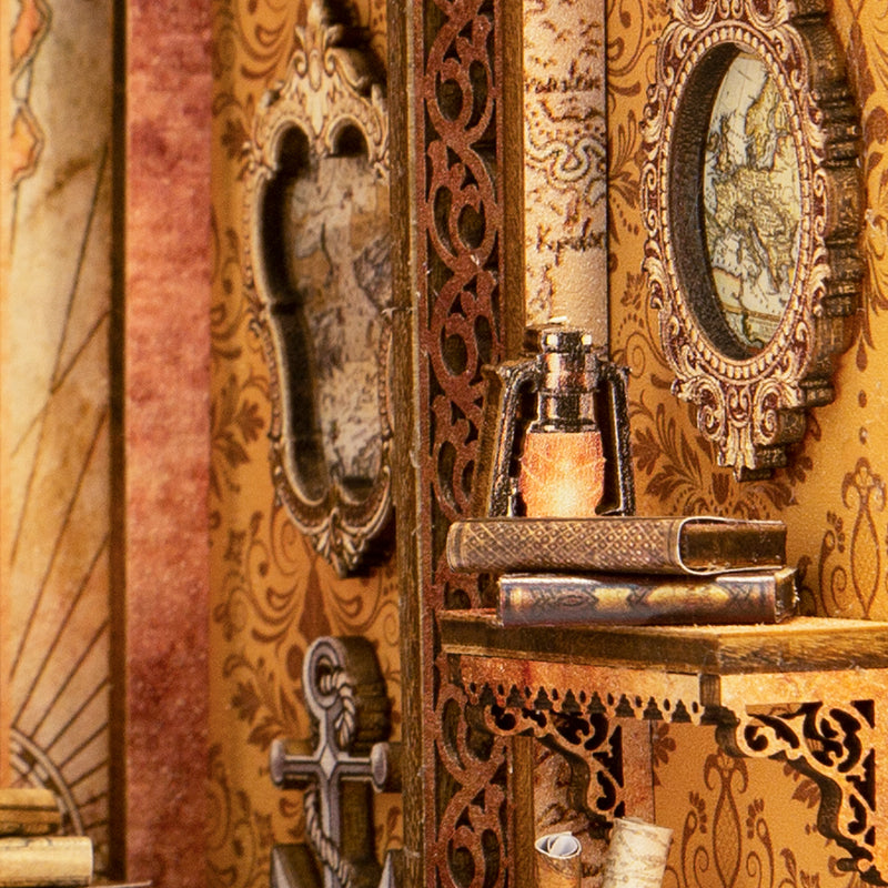 Une étagère miniature avec des éléments décoratifs, une ancre, des livres, une lampe à incandescence et des cartes encadrées.