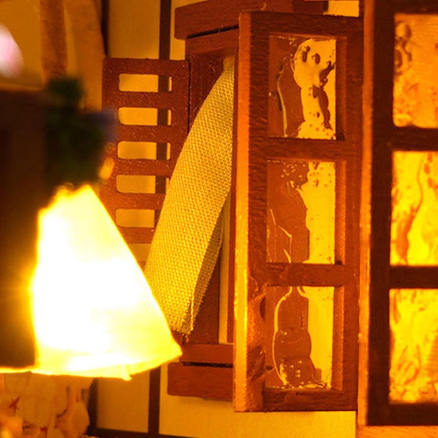 Intérieur d’une maison miniature avec des panneaux de fenêtres illuminés et une tenture en tissu.
