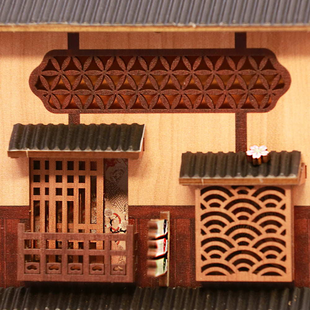 Façade d’un bâtiment japonais traditionnel miniature avec des détails en bois complexes.