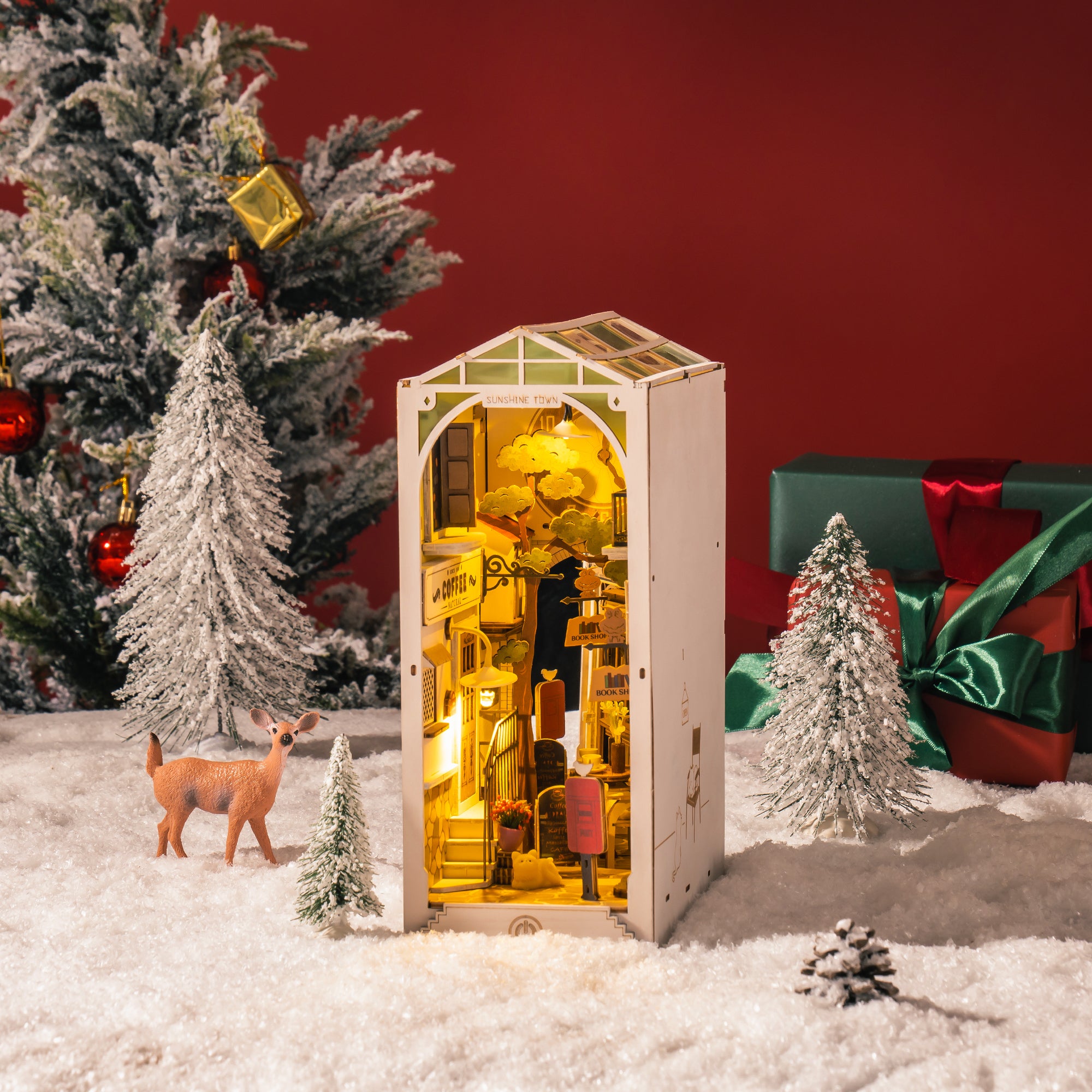 Un diorama miniature illuminé d’une scène de rue européenne, enfermé dans un livre blanc en forme de maison.