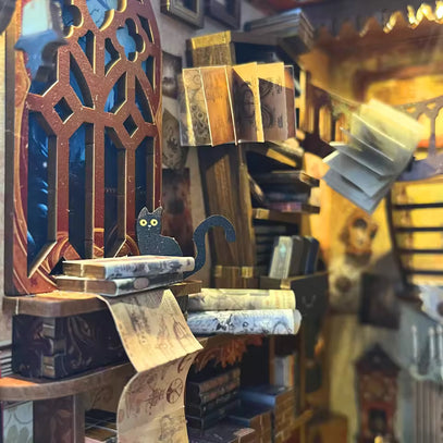 Diorama miniature représentant une scène de bibliothèque avec une figurine de chat noir.