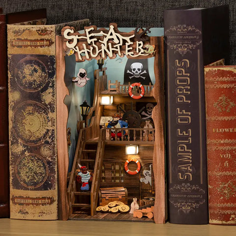 Un diorama détaillé en bois d’un bateau pirate, avec des figurines, des lumières et des accessoires, conçu pour s’insérer entre des livres.