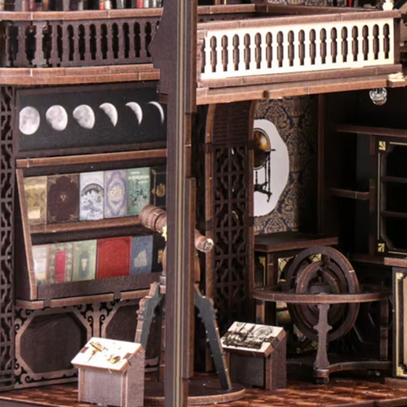 Modèle miniature en bois à plusieurs niveaux d’un cabinet de travail ou d’une bibliothèque, avec des étagères contenant de petits livres, des instruments astronomiques et des balustrades décoratives.