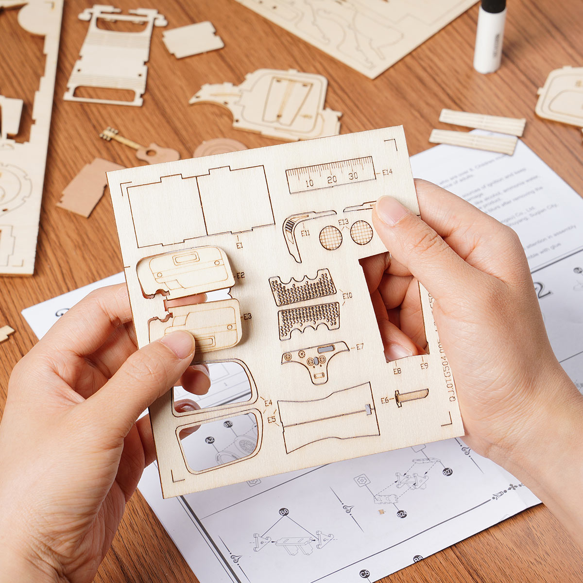 Un kit de modélisation en bois découpé au laser, comprenant diverses pièces de voiture à assembler.