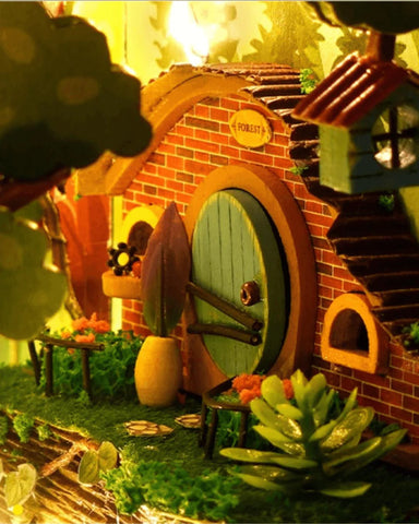 Une maison de hobbit miniature avec une porte ronde verte.