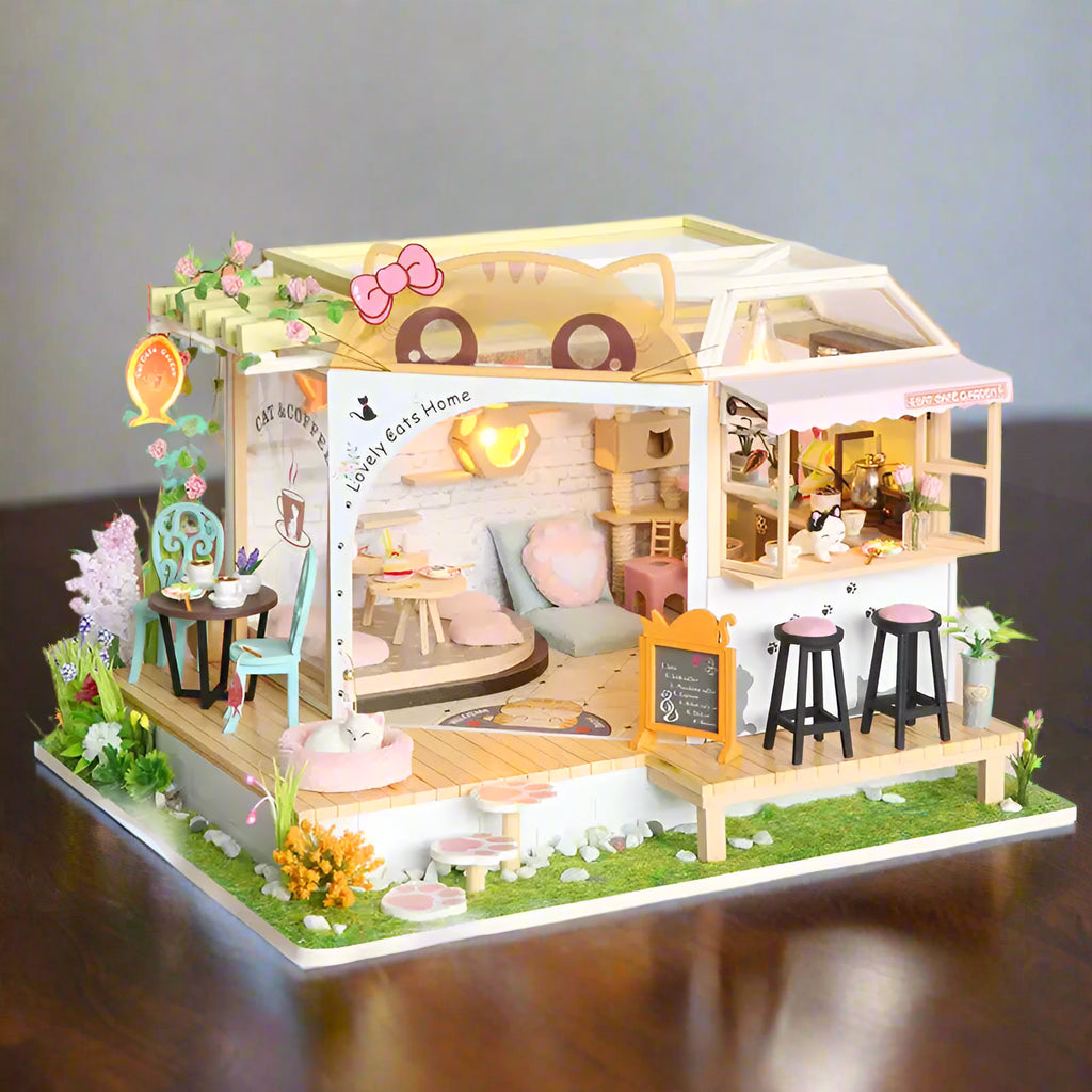 Une maison de poupée miniature en kit conçue comme un café pour chats avec plusieurs pièces et un patio extérieur.